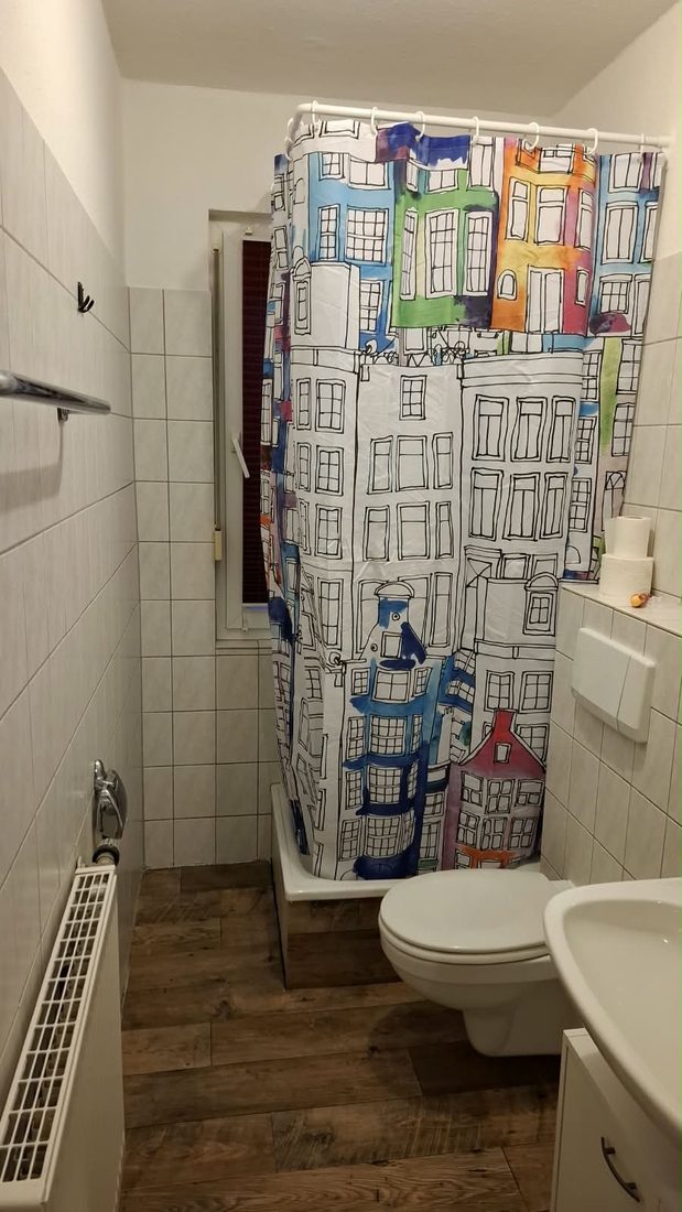 Gefliestes Duschbad mit buntem Duschvorhang