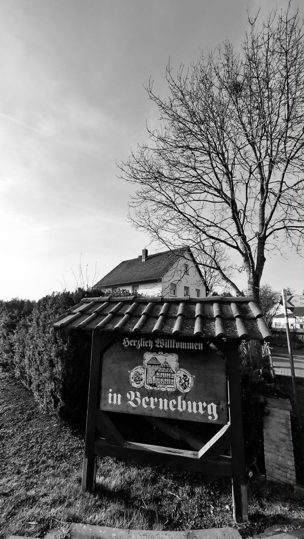 Holzschild Herzlich Willkommen in Berneburg, dahinter das Haus