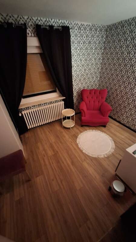 Zimmer 4 mit rotem Ohrensessel und gemusterter Tapete