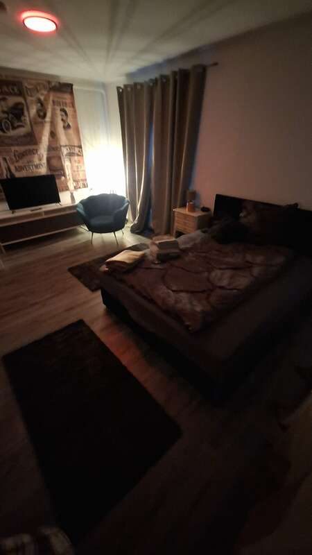 Zimmer 1 mit Doppelbett, Fernseher, Sessel und Vintage-Plakatwand