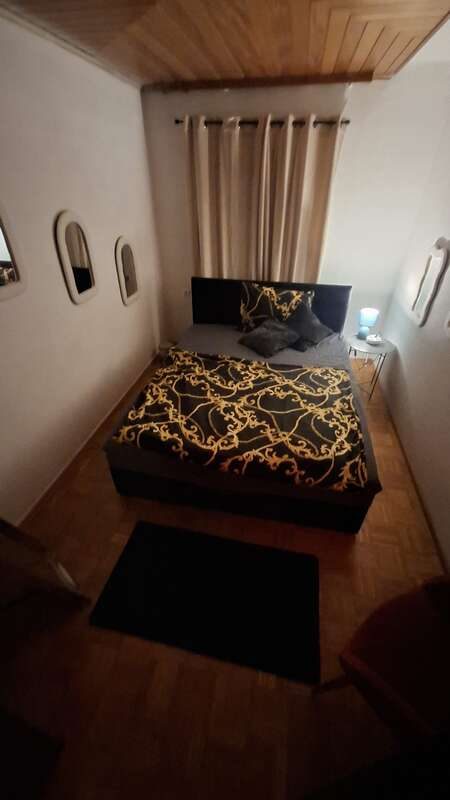 Zimmer 4 mit Doppelbett, schwarz-goldener Bettwäsche und Holzdecke