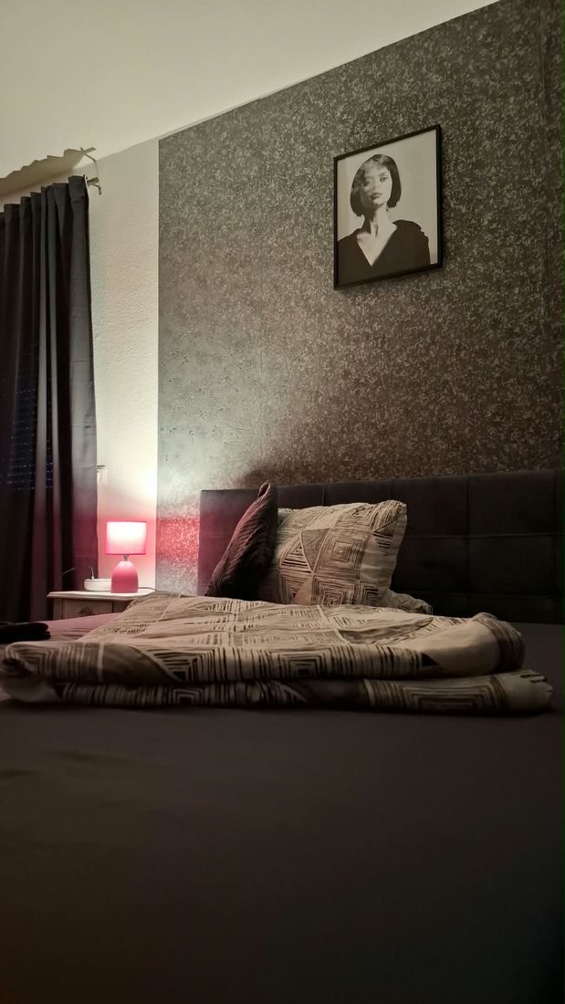 Bett vor dunkler Wand mit Schwarzweiß-Portrait